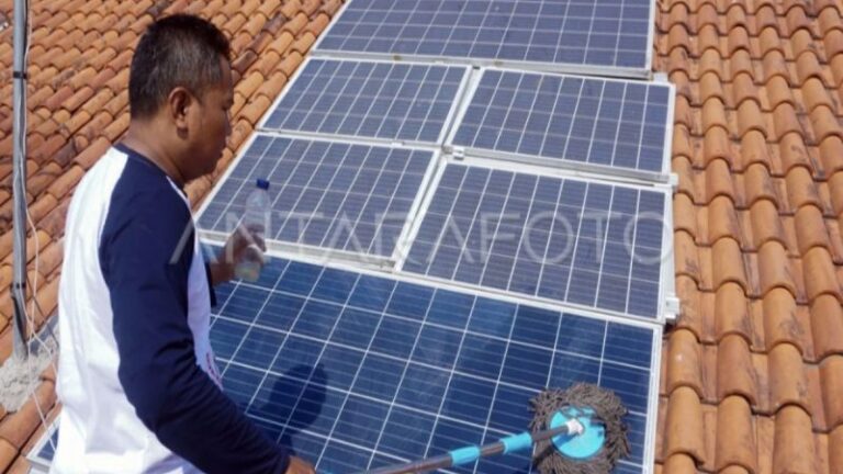 Ilustrasi- Seorang warga pemilik panel surya membersihkan panel Pembangkit Listrik Tenaga Surya (PLTS) di atap rumahnya.