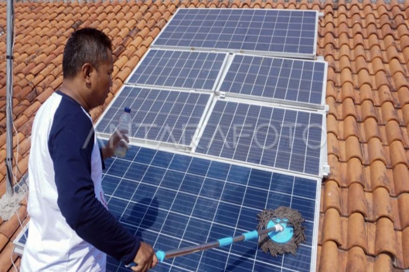Ilustrasi- Seorang warga pemilik panel surya membersihkan panel Pembangkit Listrik Tenaga Surya (PLTS) di atap rumahnya.